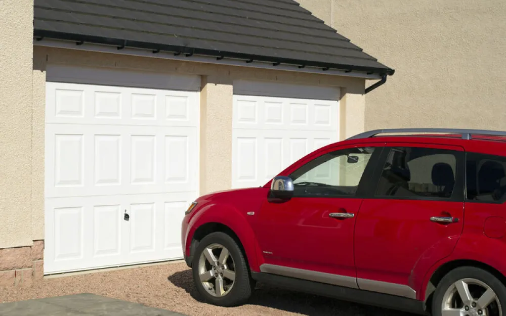 Red car parked in front of white garage door