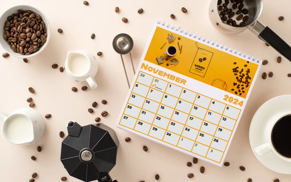 Printed calendar promotional for coffee supply company on a table with coffee, coffee beans, and milk
