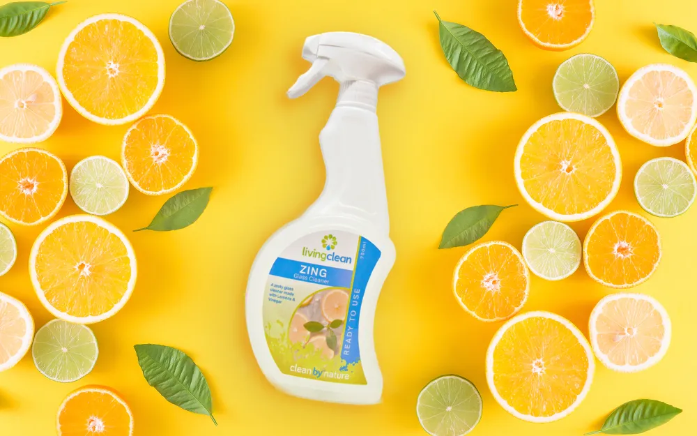 Living Cleans Glass Cleaner laying on yellow background with citrus fruits