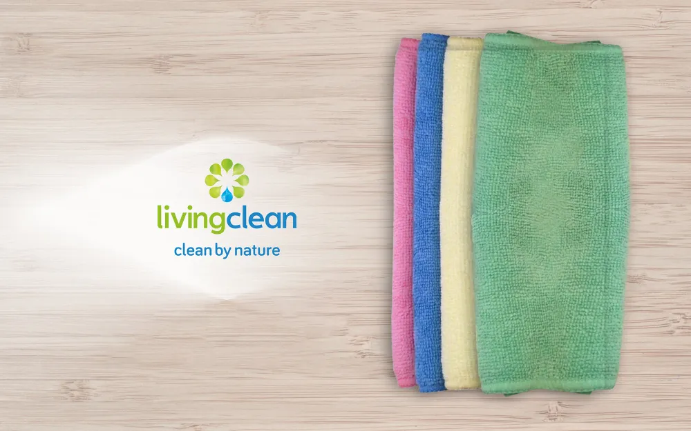 Microfibre cloths laying on a table next to Living Clean's logo