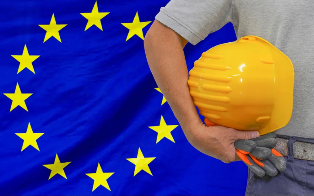 EU flag and worker holding gloves and yellow hard hat